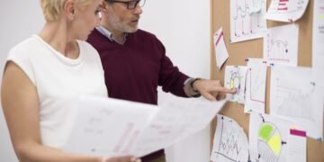man-pointing-important-papers-cork-board